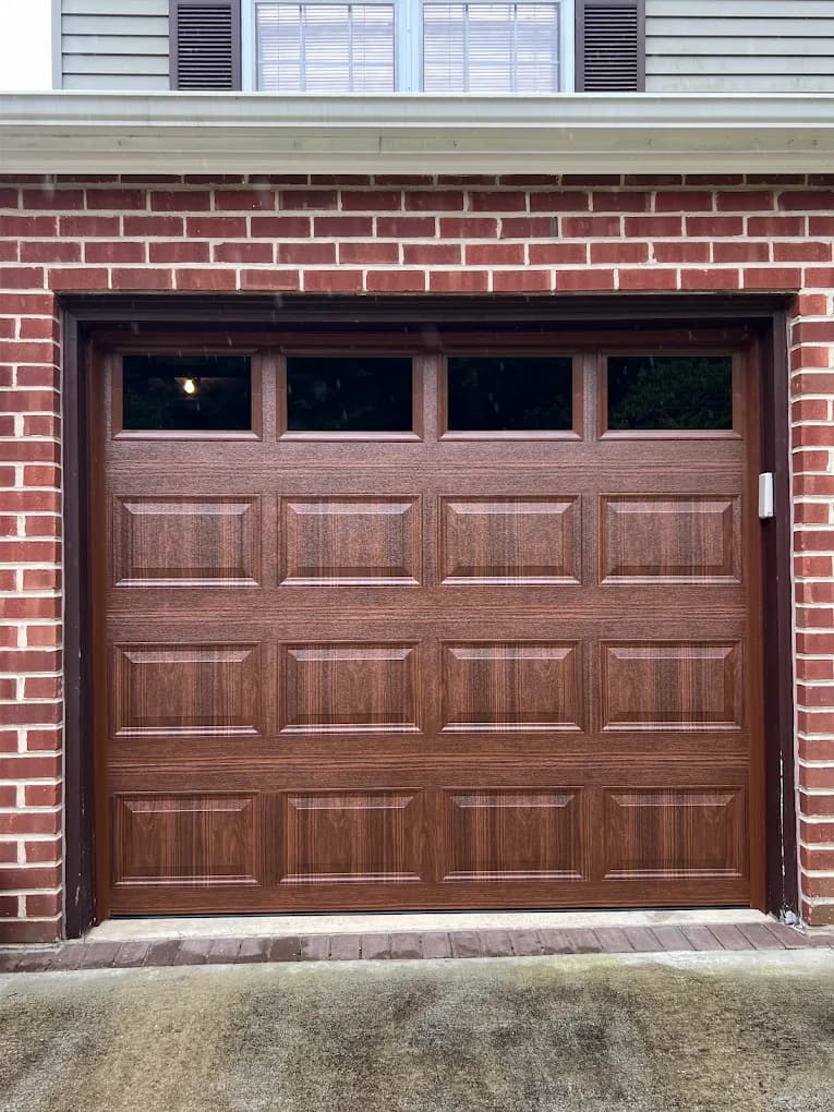 Custom wood-look double garage doors installed on a brick home